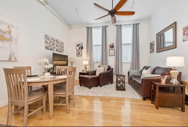 Furnished living and dining area with tall windows, shown as an example apartment at Foster Place