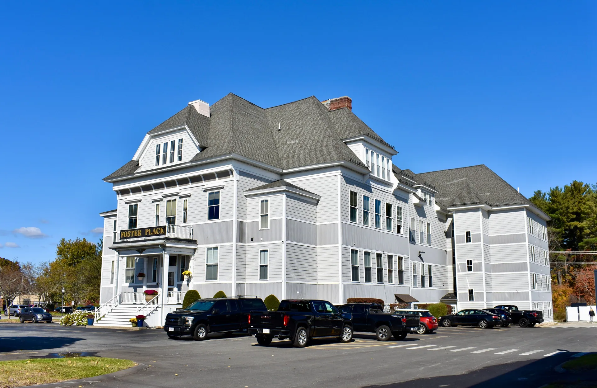 The gray and white Foster Place building, front entrance and parking area