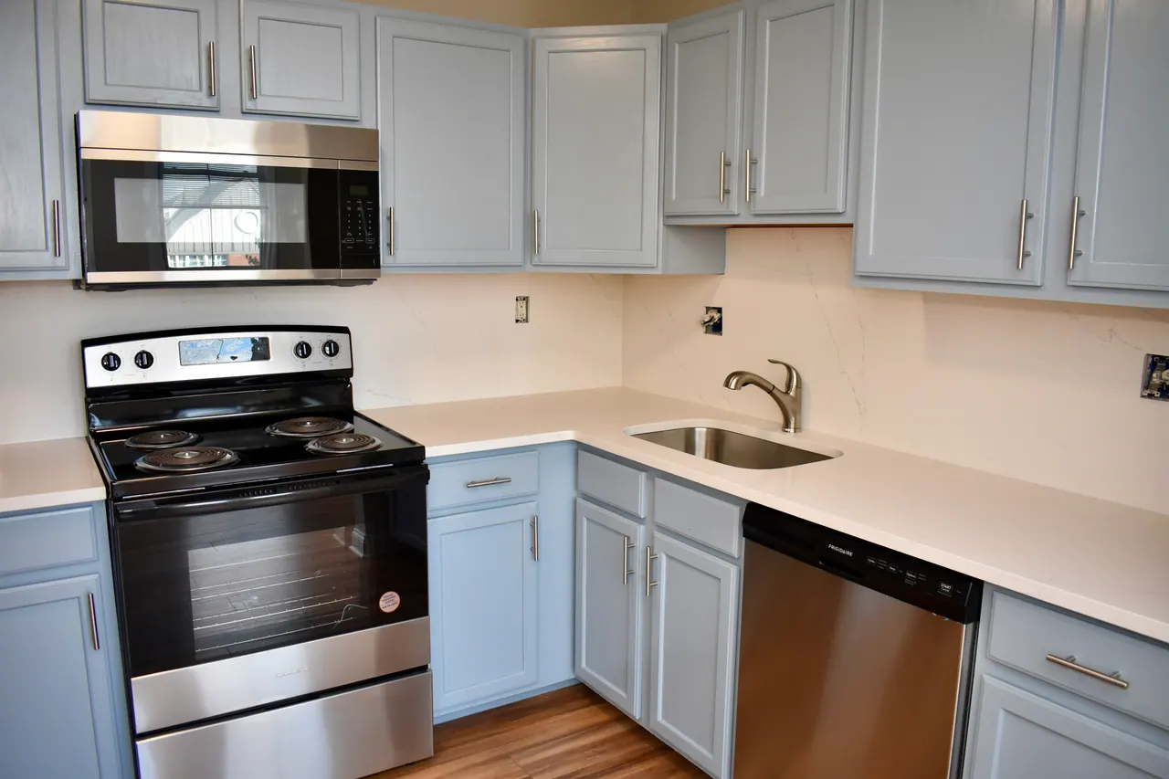 Example Foster Place kitchen with pale blue cabinets, white counters and stainless appliances